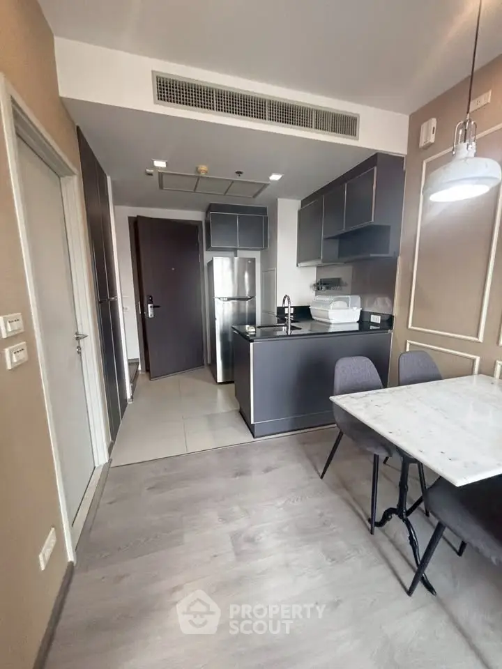 Modern kitchen with sleek cabinetry and dining area in stylish apartment.