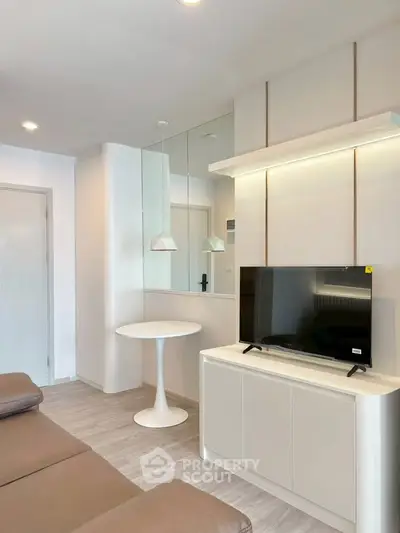 Modern living room with sleek design, featuring a TV, stylish furniture, and elegant lighting.