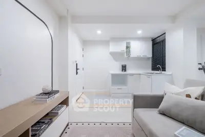 Modern minimalist living room with open kitchen layout and sleek white cabinetry.
