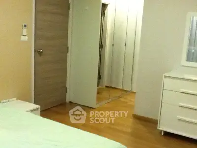 Spacious bedroom with wooden flooring and mirrored closet doors in modern apartment.