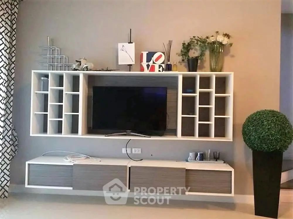 Modern living room with stylish wall-mounted entertainment center and decorative elements.