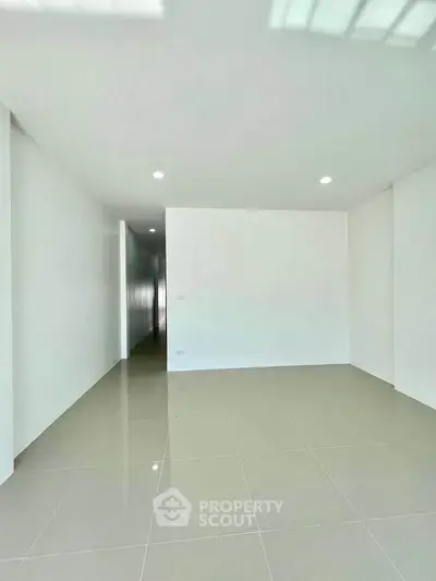 Spacious minimalist room with glossy tiled floor and recessed lighting, perfect for modern living.