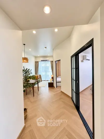 Modern apartment hallway leading to a stylish living room with natural light and elegant decor.