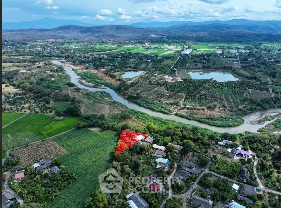 Scenic aerial view of lush green landscape with river and mountains, ideal for real estate investment.