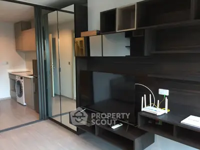 Modern living room with sleek TV unit and adjacent kitchen featuring a washing machine.