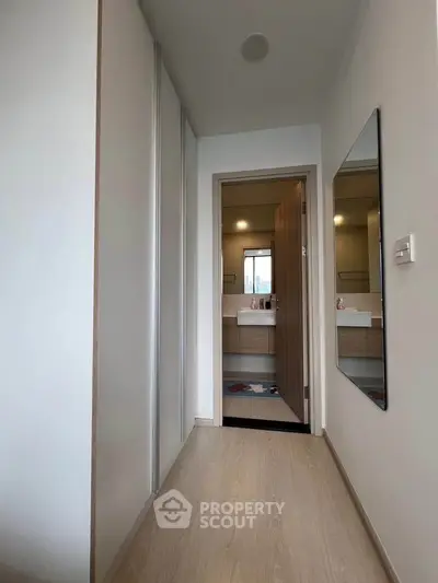 Modern hallway leading to a stylish bathroom with sleek fixtures.