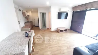 Spacious living room with wooden flooring, modern furniture, and large windows for natural light.