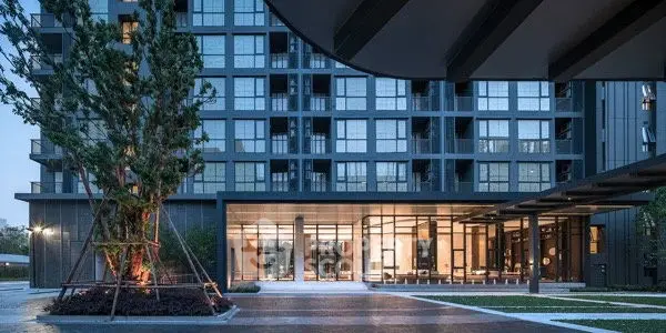 Modern luxury apartment building entrance with sleek design and landscaped surroundings.
