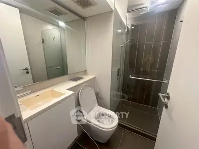 Modern bathroom with sleek design, featuring a glass-enclosed shower and contemporary fixtures.