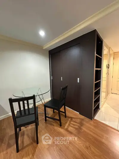Modern interior with sleek dark wood furniture and glass dining table in cozy living space.