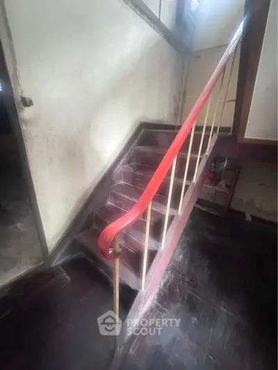 Charming vintage staircase with red handrail in a rustic home setting