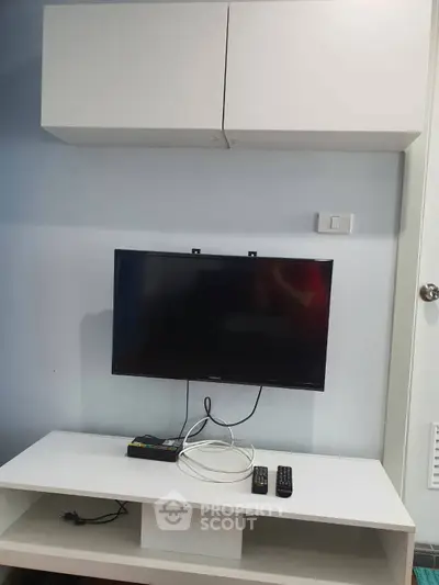 Modern living room setup with wall-mounted TV and sleek white cabinets.