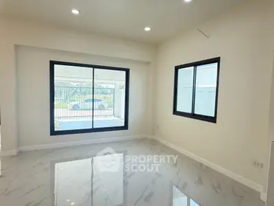 Spacious modern living room with large windows and marble flooring, offering ample natural light and elegant design.