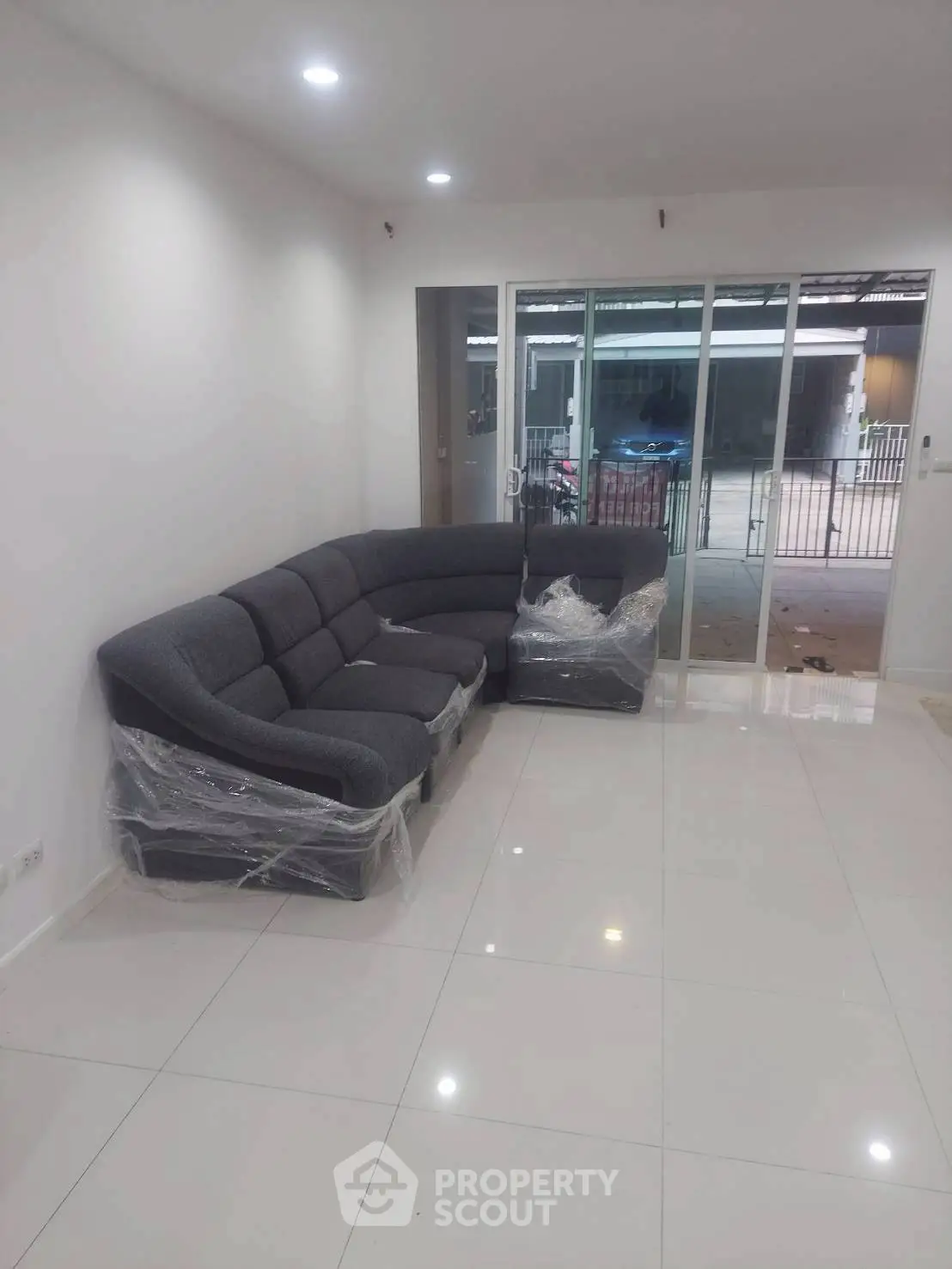 Spacious living room with modern gray sectional sofa and sliding glass doors.