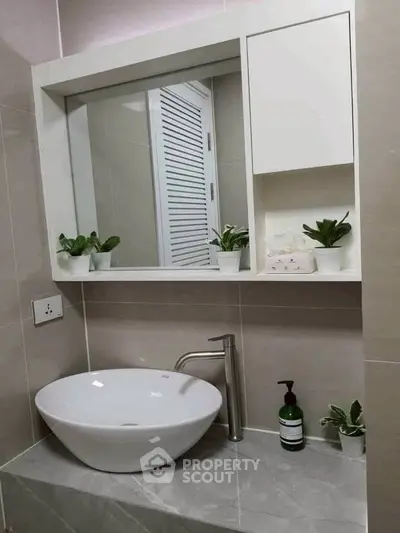 Modern bathroom with stylish sink and mirror, featuring elegant decor and plants.