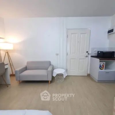 Modern studio apartment with cozy seating and compact kitchen area.