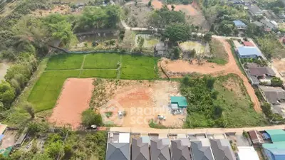 Aerial view of a residential development site with plots and surrounding greenery.