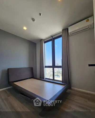 Modern bedroom with large window and city view, featuring sleek flooring and air conditioning.