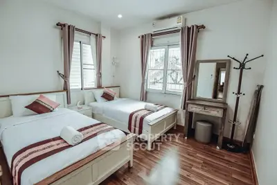 Charming twin bedroom with wooden flooring and natural light