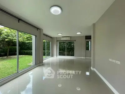 Spacious living room with large windows and garden view, perfect for natural light lovers.
