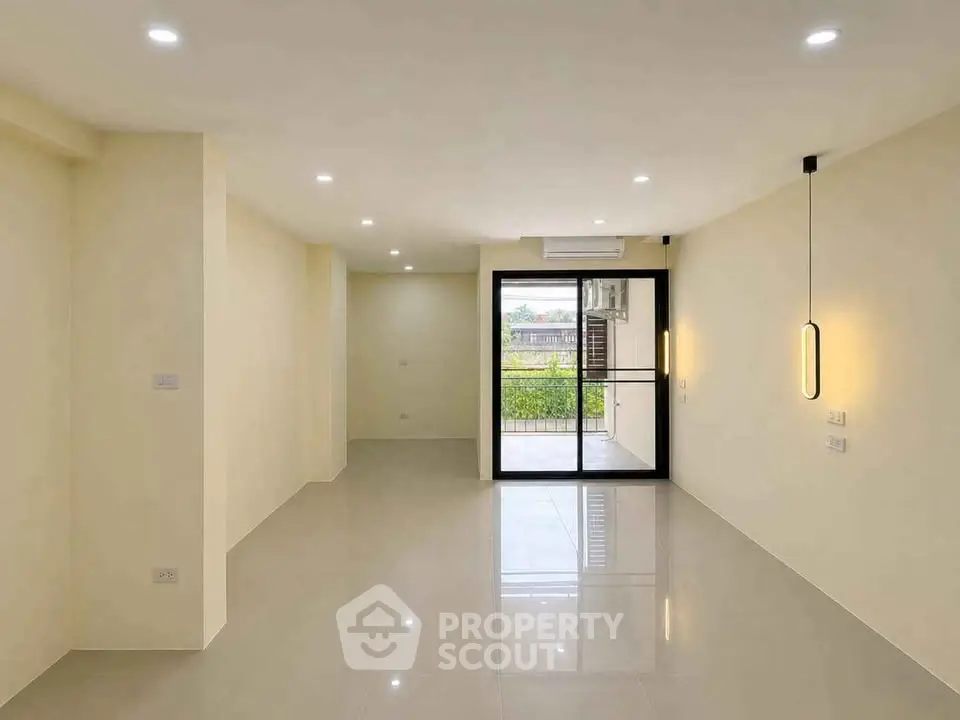 Spacious modern living room with sleek lighting and large windows opening to a balcony.