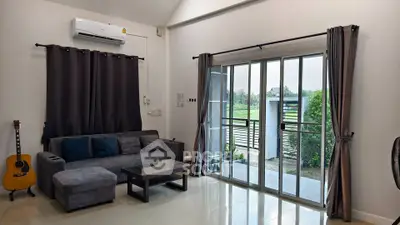 Modern living room with large sliding glass doors and cozy gray sofa, offering a serene garden view.