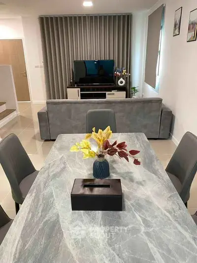 Modern living room with stylish decor and open layout, featuring a marble dining table and cozy seating area.