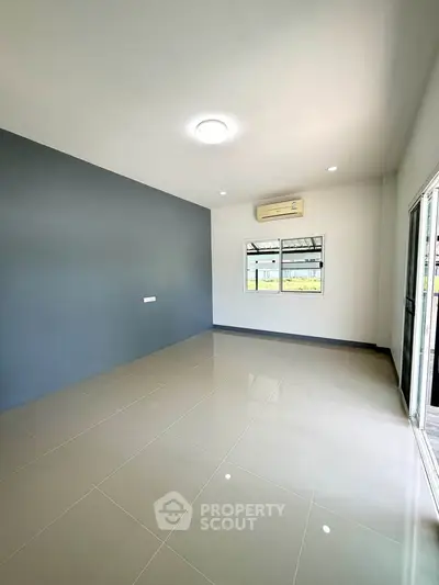 Spacious unfurnished room with large windows and air conditioning, perfect for customization.