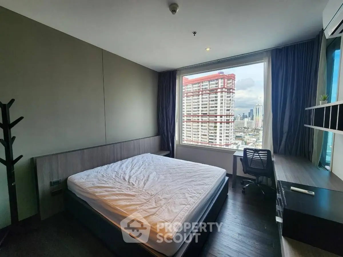 Modern bedroom with city view, featuring a large window and sleek furnishings.