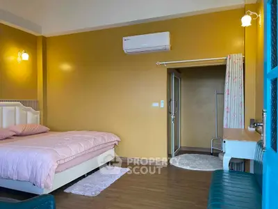 Cozy bedroom with warm yellow walls, featuring a comfortable bed and modern air conditioning unit.