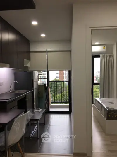 Modern apartment with kitchen and bedroom, featuring a balcony view.