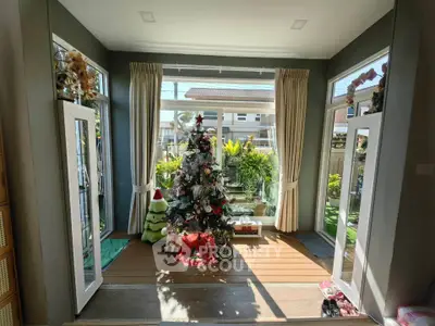Bright living room with Christmas tree and garden view, perfect for holiday gatherings.