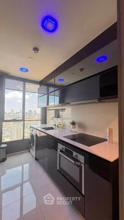 Modern kitchen with sleek black cabinets and stunning city view, featuring built-in oven and washing machine.