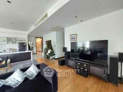 Spacious living room with modern decor and Christmas tree, open layout to kitchen area.