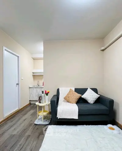 Cozy living room with modern sofa and small kitchenette, perfect for urban living.