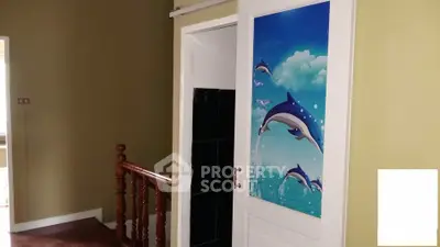Charming interior hallway with dolphin-themed door and wooden railing.