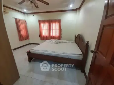Cozy bedroom with wooden bed frame and ceiling fan, featuring warm lighting and red curtains.