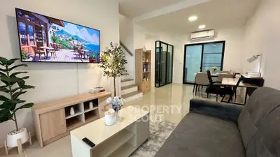 Modern living room with stylish decor and open dining area, featuring a wall-mounted TV and elegant furnishings.