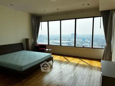 Spacious bedroom with panoramic city view and hardwood floors