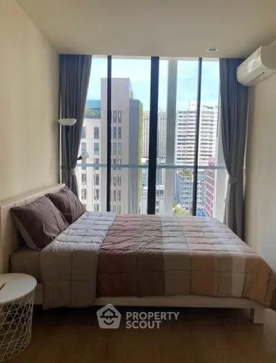 Modern bedroom with city view, featuring large windows and stylish decor.
