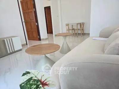 Modern living room with elegant furniture and open layout, featuring a cozy beige sofa and stylish wooden tables.