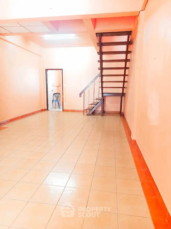 Spacious interior with tiled flooring and modern staircase in a bright open layout.