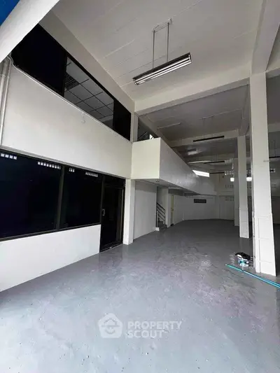 Spacious industrial-style interior with high ceilings and mezzanine level, ideal for commercial use.