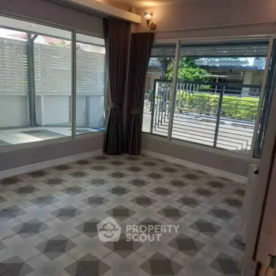 Spacious room with large windows and patterned tile flooring, offering ample natural light and garden view.