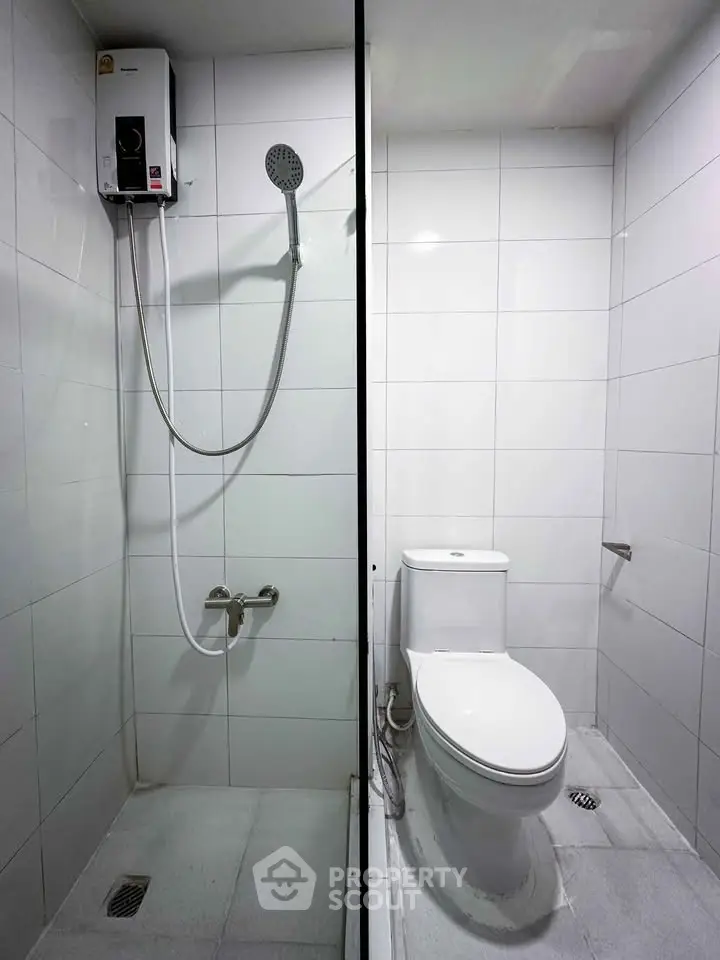 Modern bathroom with shower and toilet in sleek white tile design.