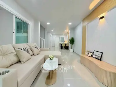 Modern living room with elegant decor and spacious layout, featuring a cozy beige sofa and stylish lighting.