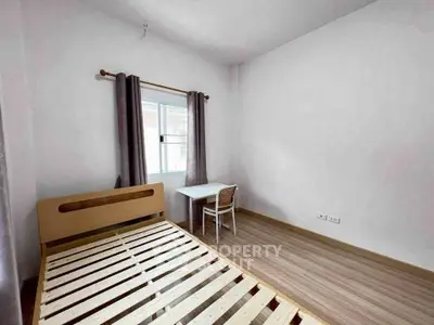 Minimalist bedroom with wooden bed frame and small study desk near window