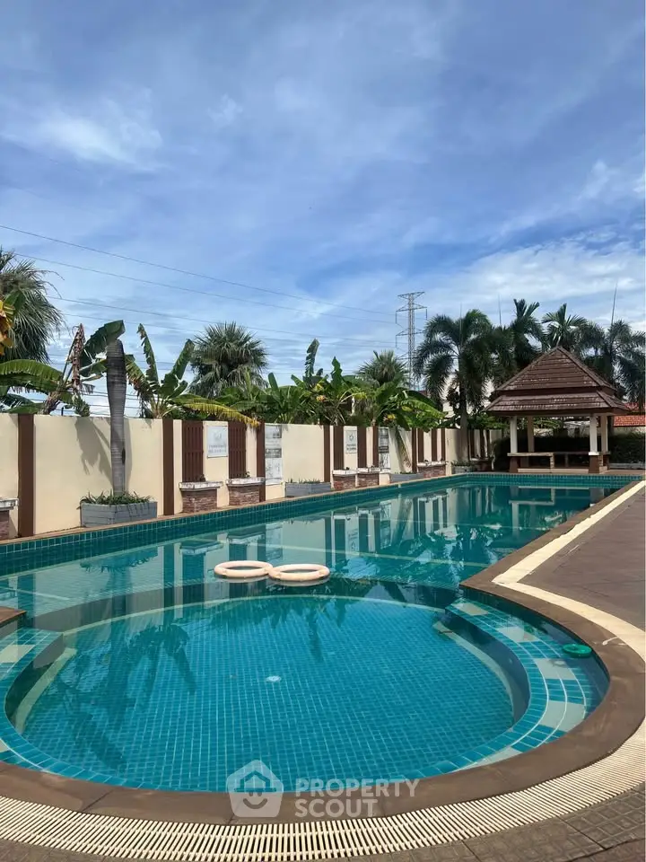 Luxurious outdoor swimming pool with tropical landscaping and clear blue skies, perfect for relaxation and leisure.