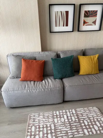 Modern living room with stylish gray sofa and colorful cushions, featuring contemporary wall art and cozy ambiance.