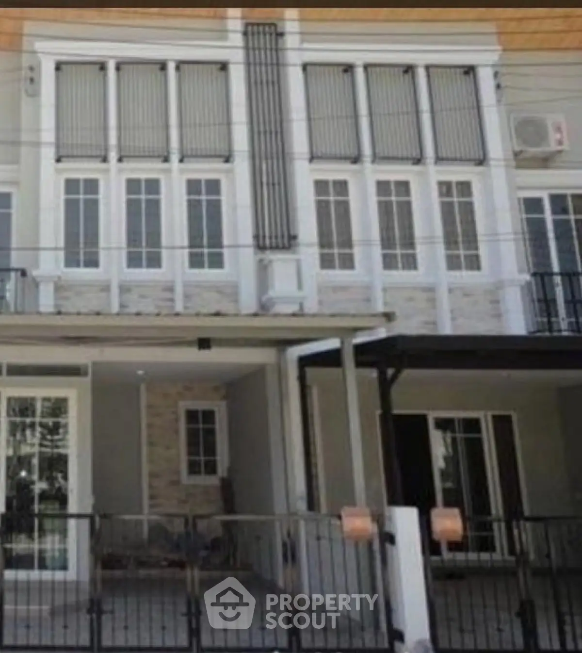 Modern townhouse exterior with gated entrance and large windows.